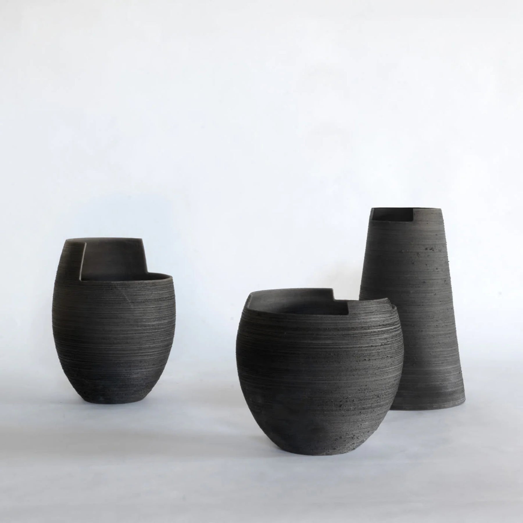 Three black ceramic vases of different sizes on a white background