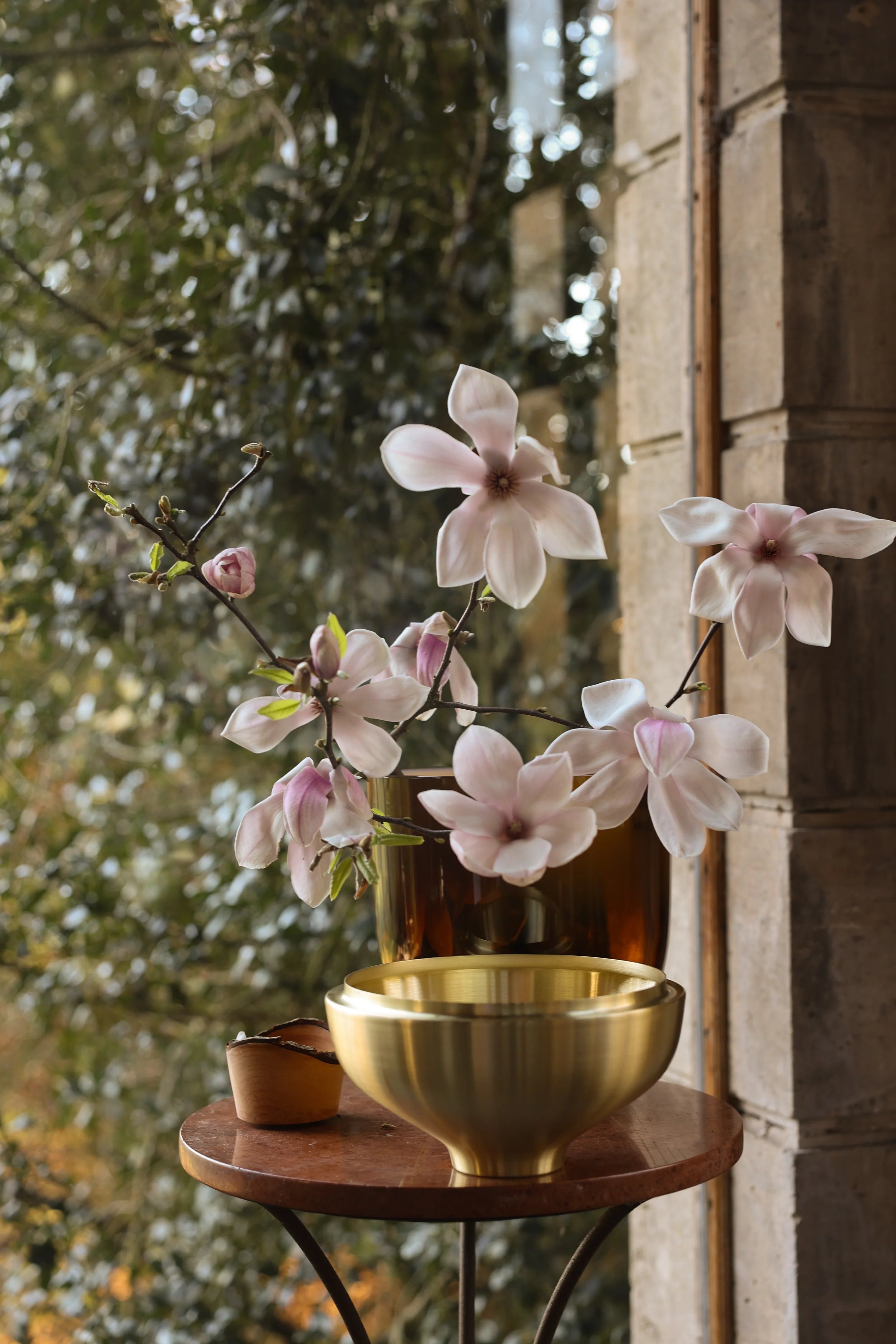 Pink flowers in a vase on a wooden table with a blurred natural background